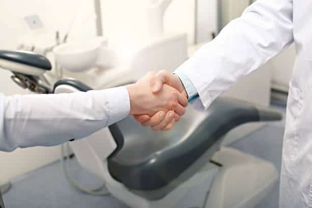 A dentist and a patient are handshaking